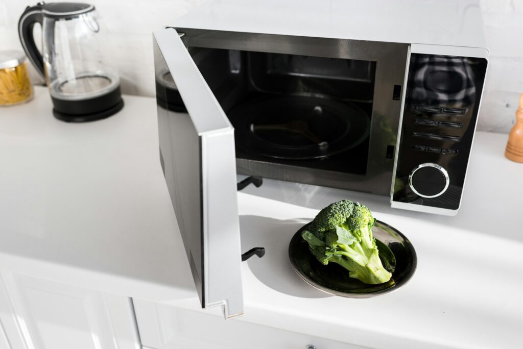 plate with broccoli on plate near microwave in kitchen