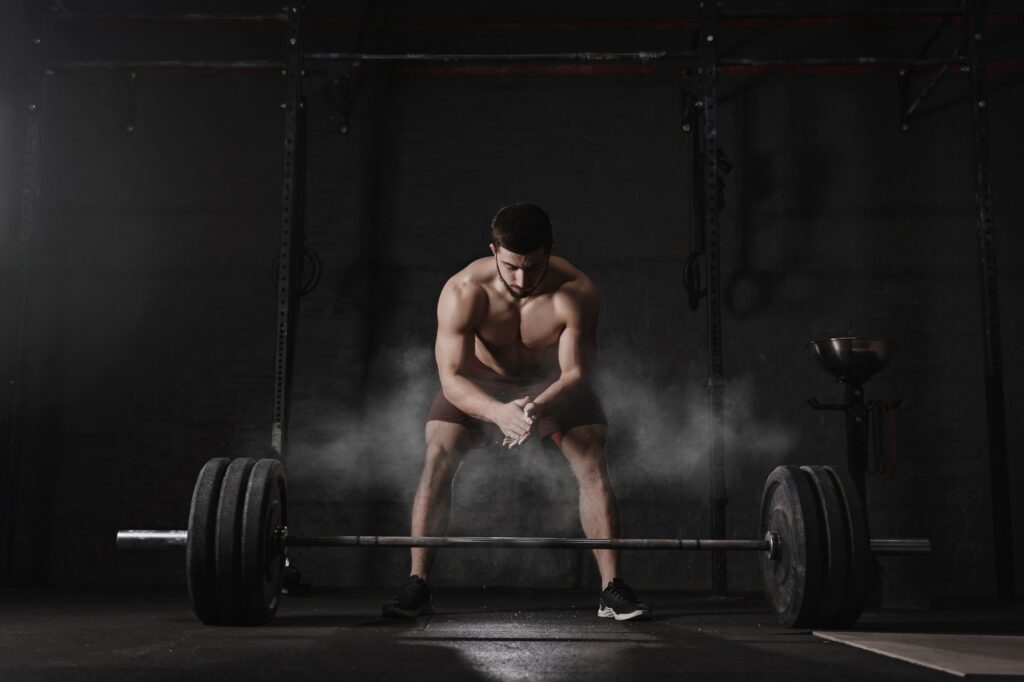 Crossfit athlete clapping hands and preparing for weight lifting at the gym