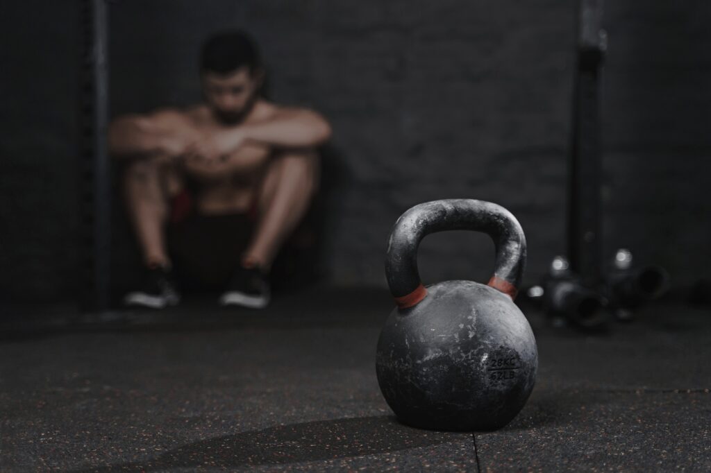 Sporty man sitting at the gym suffering breakdown to overcome