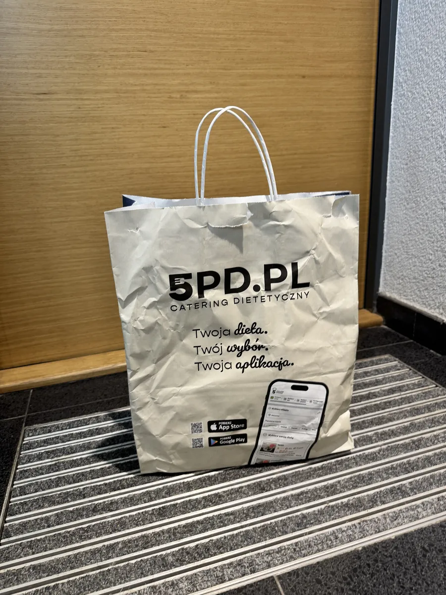 Papierowa torba 5PD.pl z dostawą cateringu postawiona na wycieraczce pod drzwiami