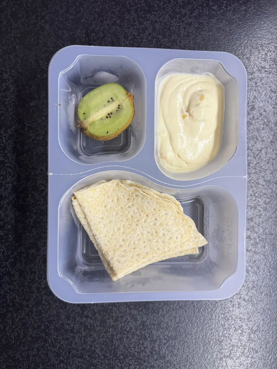 Otwarte pudełko Kuchni Vikinga: naleśnik, osobna duża porcja twarożku mango-marakuja i kiwi