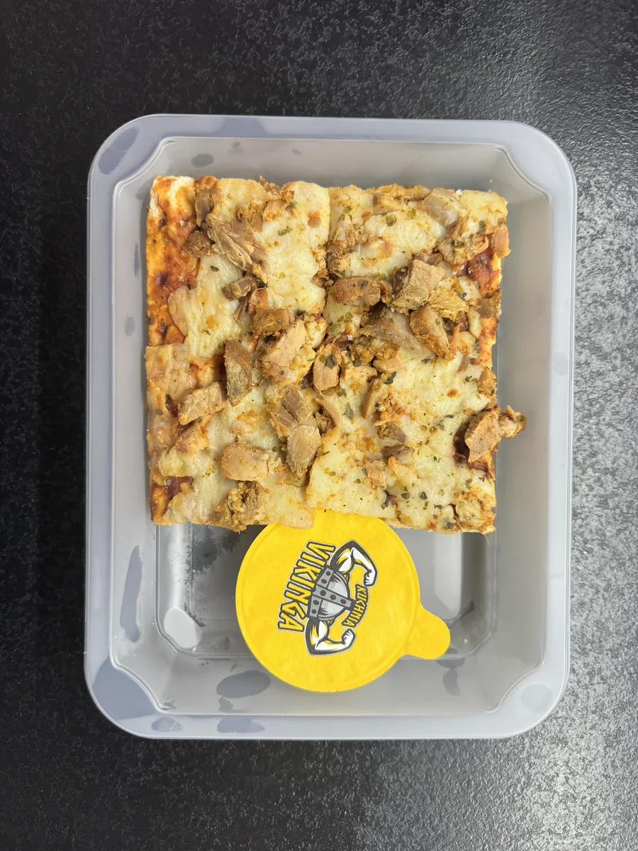 Otwarte pudełko Kuchni Vikinga z pizzą z pieczoną wieprzowiną i osobnym pojemnikiem sosu czosnkowego