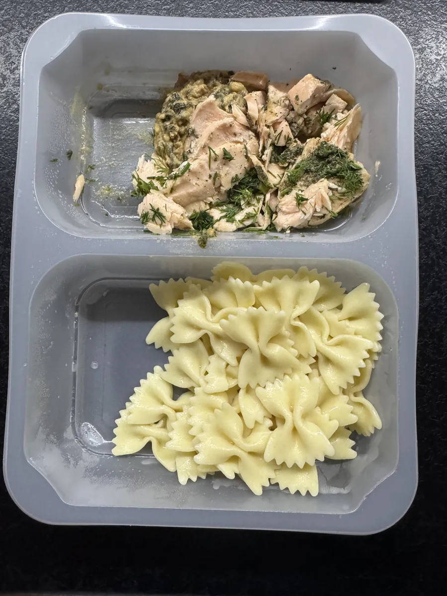 Otwarte pudełko Robin Food: makaron farfalle w jednej komorze, pieczony łosoś ze szpinakiem w drugiej