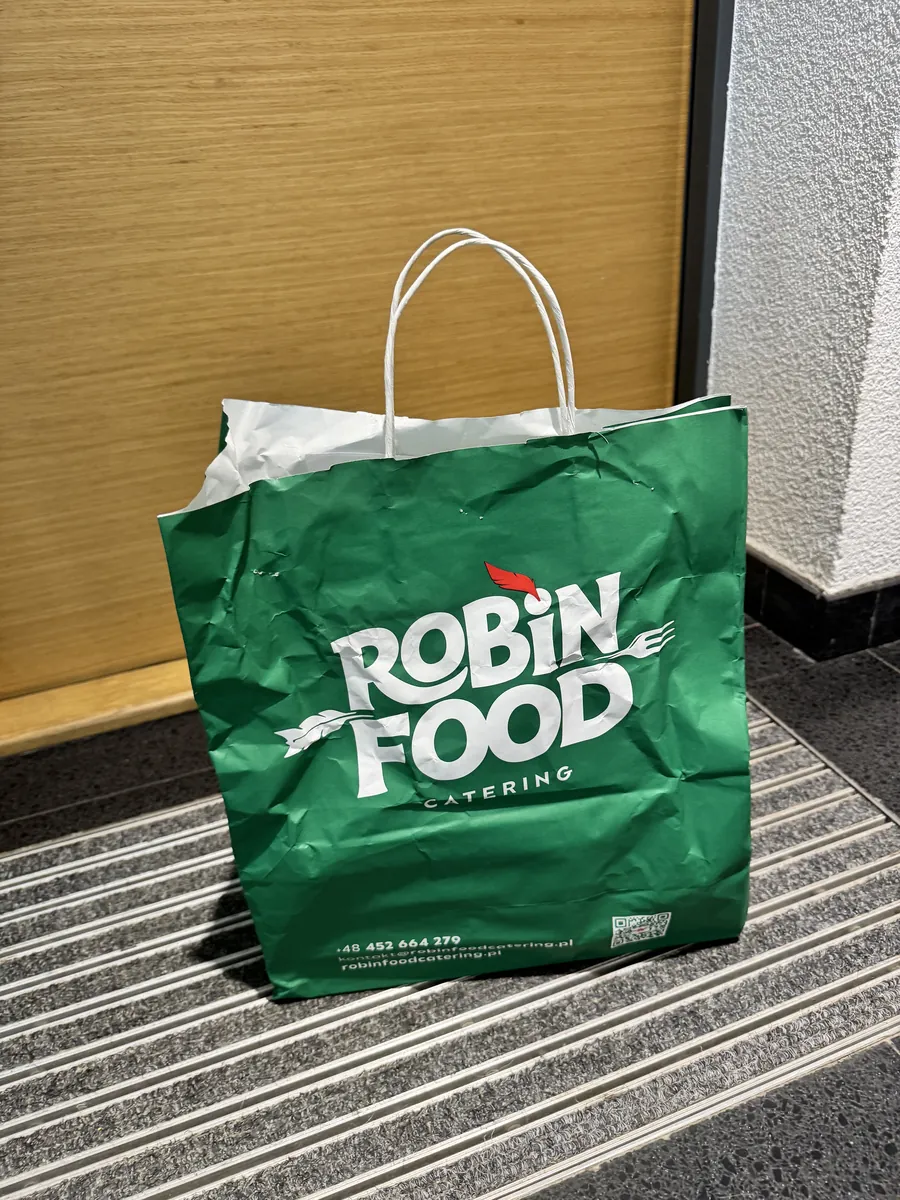 Zielona papierowa torba Robin Food z dzienną dostawą posiłków pod drzwiami mieszkania