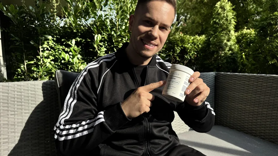 Adrian Domagalski, trener personalny z Poznania, trzyma puszkę ForMeds POWDER creatine i wskazuje na nią palcem